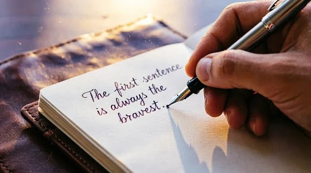 Hand holding silver fountain pen writing 'The first sentence is always the bravest.' in leather notebook, rich purple-gold dawn light, shallow depth of field (AI-generated illustration)