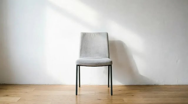 empty chair facing blank wall, soft morning light (AI-generated illustration)