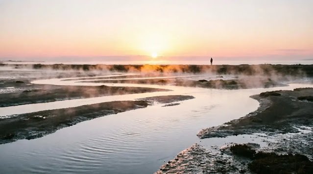 Wide river at sunrise with a distant a human figure silhouette(AI-generated visual)