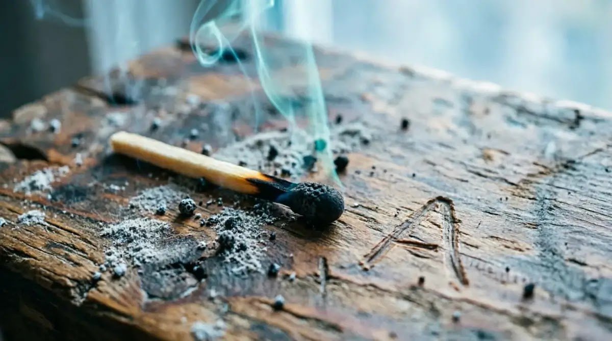 Burnt match wooden table smoke traced letter A dust (AI-generated illustration)