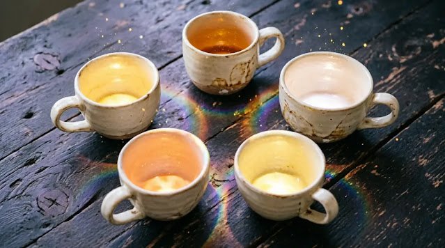 Five diverse cream ceramic cups glowing with unique colored lights in a circle (AI-generated illustration)