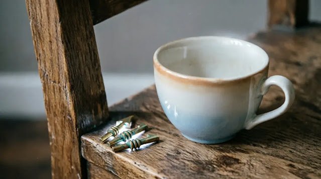 Ceramic teacup on aged wooden chair, small brass markers forming circle pattern, subtle steam spiral, soft natural lighting (AI-generated illustration)